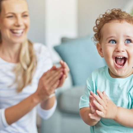 Happy, clapping hands and mother and son playing in the living room of their family home. Happiness, love and energy of parent and toddler having fun and cheering together in the lounge of a house