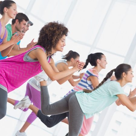 Fitness class and instructor doing pilates exercise in a bright room