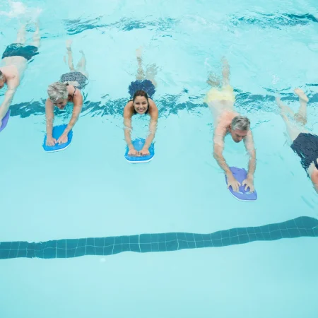 hohe-winkelansicht-von-alteren-schwimmern-und-trainern-die-mit-kickboards-im-pool-schwimmen