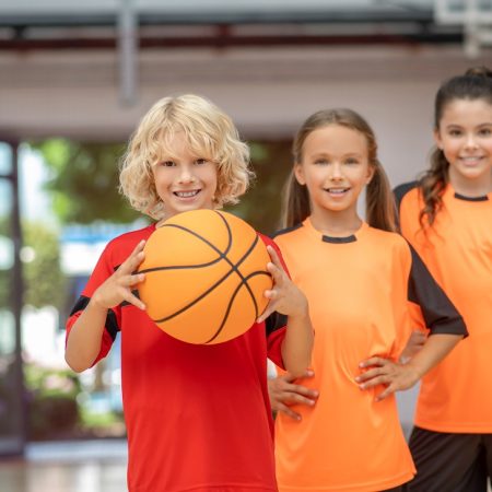 Like to play. Kids in sportswear standing with a ball and looking enjoyed
