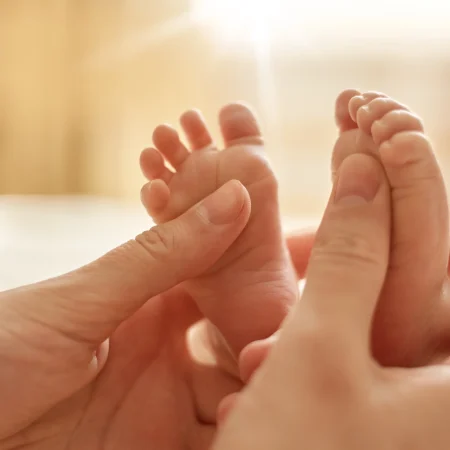 mum-making-baby-massage-mother-massaging-infant-bare-foot-preventive-massage-for-newborn-mommy-stroking-the-baby-s-feet-with-both-hands-on-light-background