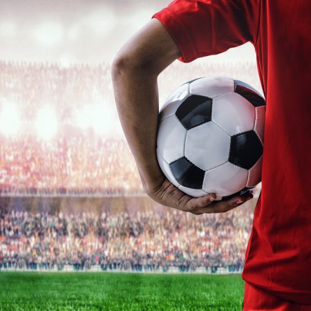 soccer football player in red team concept holding soccer ball in the stadium
