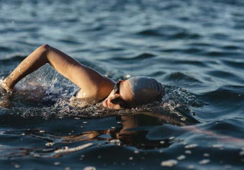 seitenansicht-der-schwimmerin-mit-mutze-und-schutzbrille-die-im-wasser-schwimmen